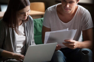 Serious Millennial Couple Paying Bills Online On Laptop At Home,